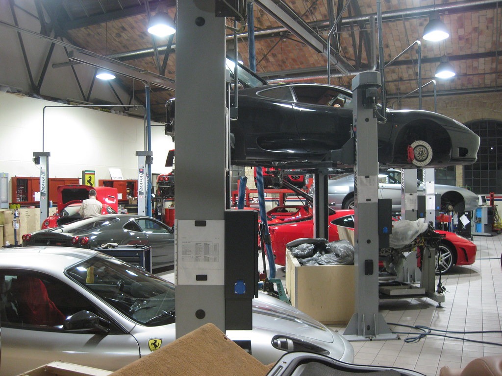 Luxury sports cars are in a well-equipped garage with lifts and tools
